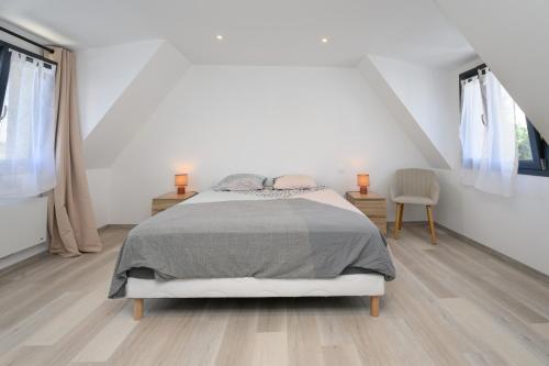 a white bedroom with a bed and two windows at Ker Marin -Maison Refuge Des Marées in Sarzeau