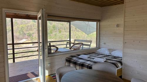 a room with a bed and a balcony with a table at Prozori Boiky in Lopushanka-Khomyna
