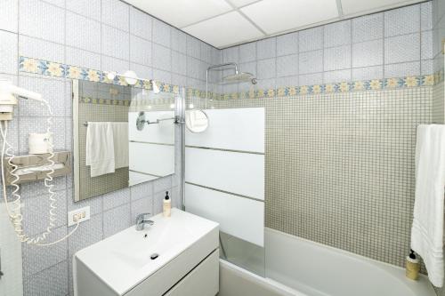a white bathroom with a sink and a mirror at Palatium Mari in Capri