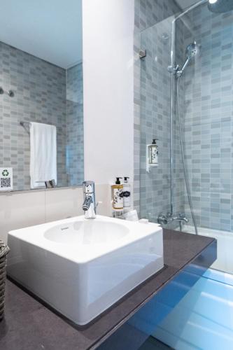 a bathroom with a white sink and a shower at Villa Doris Suites in Lagos