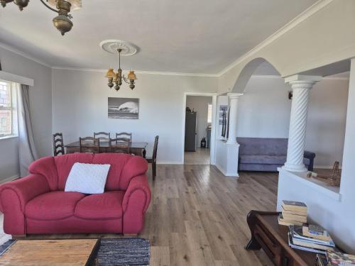a living room with a red couch and a table at Magna Apartment in Jeffreys Bay