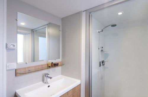 a bathroom with a sink and a shower with a mirror at Siblu Camping Meerwijck in Kropswolde