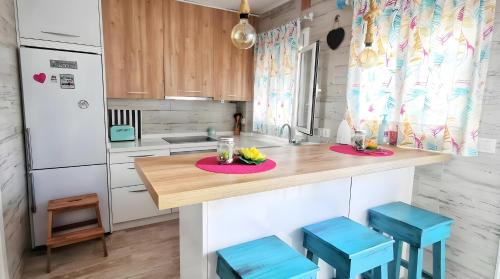 a kitchen with a wooden counter top with blue stools at Apartamento Aguamarina con terraza in Chiclana de la Frontera