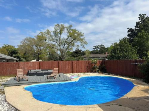 a swimming pool in a backyard with a wooden fence at A Poolside Paradise in Pensacola