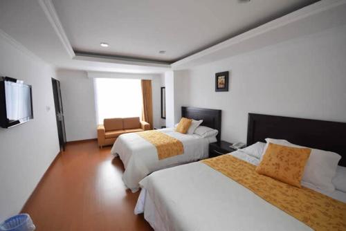 a hotel room with two beds and a chair at HOTEL ZAFIRO PLAZA in Tunja