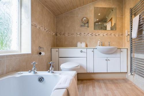 a bathroom with a tub and a toilet and a sink at The White House, Tunstall in Tunstall