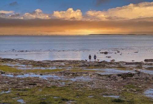 two people walking on the beach with their surfboards at Chalet Studio #12 - Relaxing getaway with Wifi & AC in Cap-Saint-Ignace