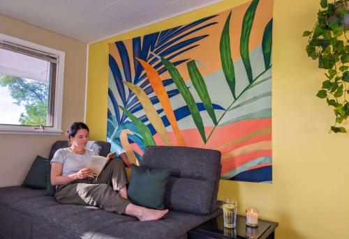 a woman sitting on a couch reading a book at Chalet Studio #12 - Relaxing getaway with Wifi & AC in Cap-Saint-Ignace