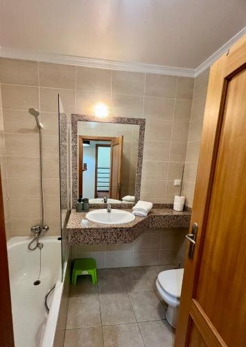 a bathroom with a sink and a toilet and a mirror at Caniço Lodge in Caniço