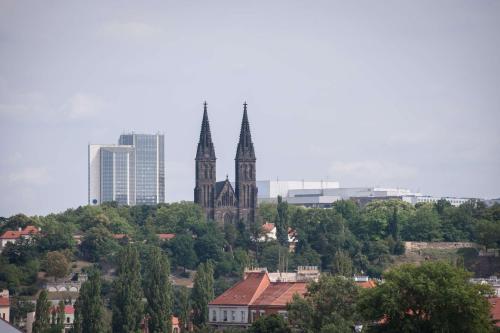a church with two towers in a city with trees at Occidental Praha Five in Prague