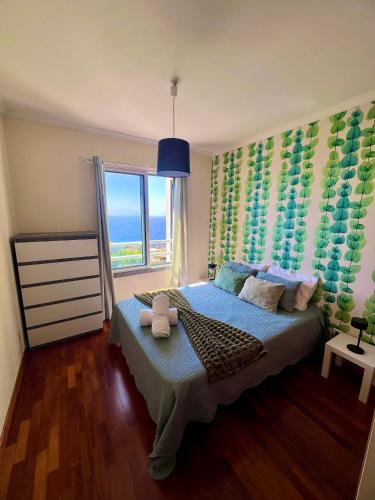 a bedroom with a bed and a large window at Caniço Lodge in Caniço