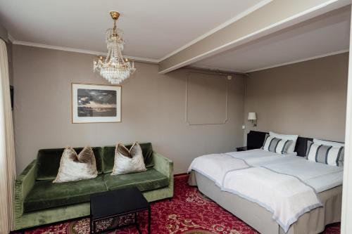 a bedroom with a bed and a couch and a chandelier at Klækken Hotel in Hønefoss