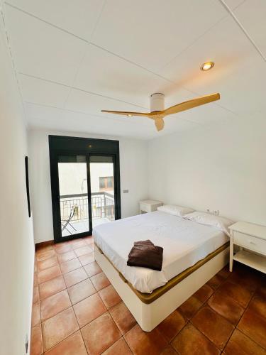 a white bedroom with a bed and a window at Apartamentos Blanes Petit in Blanes