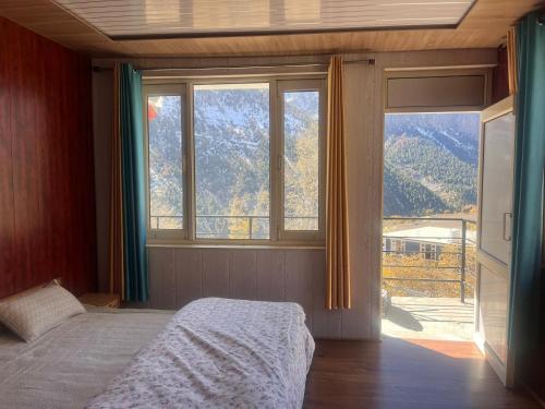 a bedroom with a bed and a large window at beheney Homestay gondhla in Kyelang
