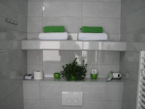 a bathroom with white towels and a plant on a shelf at Eva Luxury Rooms & Apartments in Plitvička Jezera