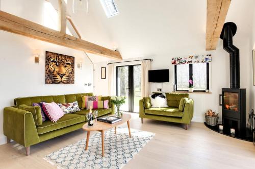 a living room with a green couch and a fireplace at Little Larks Barn in Felsted Station