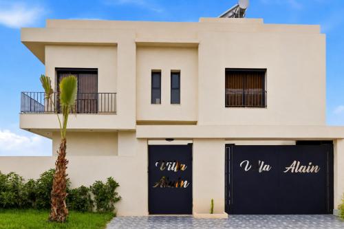 a white house with a palm tree in front of it at Riad Villa Alain in Nouaceur
