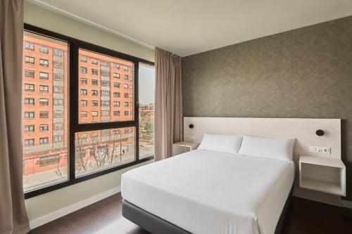 a bedroom with a white bed and a large window at RICE Bulevar in Burgos
