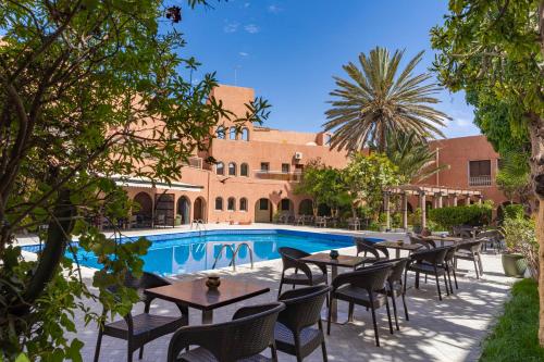 a patio with tables and chairs next to a pool at Tiznit Hotel in Tiznit