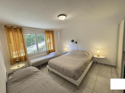 a bedroom with two beds and a window at Logis PONIENTE in Arles-sur-Tech