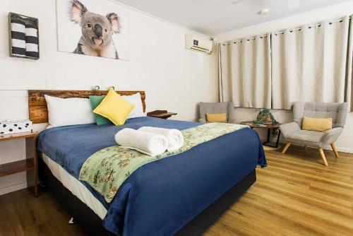 a bedroom with a blue bed and a chair at Kilcoy Motel in Kilcoy