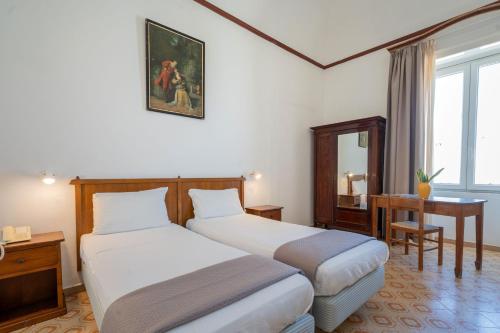 a hotel room with two beds and a desk and a mirror at Pensione Di Lustro in Forio d'Ischia