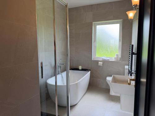 a bathroom with a tub and a toilet and a sink at Number 6 Westpark Spanish Point in Spanish Point