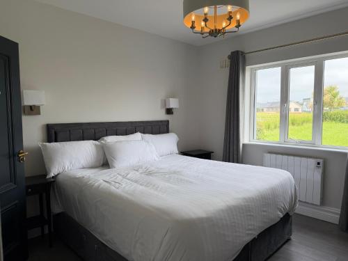 a bedroom with a large white bed with a window at Number 6 Westpark Spanish Point in Spanish Point