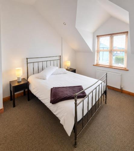 a bedroom with a large bed and a window at Kilkee Townhouse by Trident Holiday Homes in Kilkee