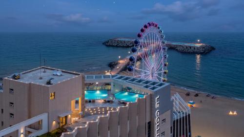 a ferris wheel next to a building and the ocean at Le Collective Sokcho Beach in Sokcho