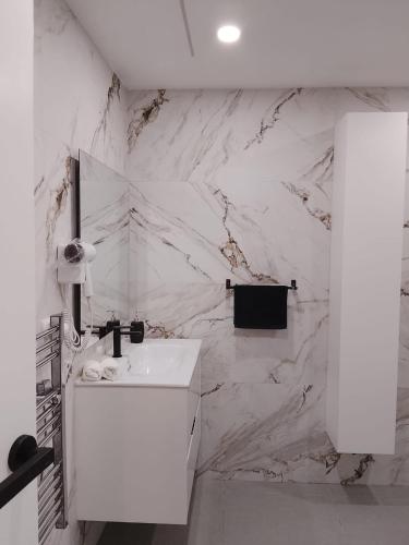 a white bathroom with a sink and a marble wall at HcHOME in Algeciras