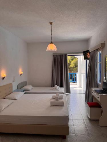 a bedroom with two beds and a large window at Vassilis Studios in Poros