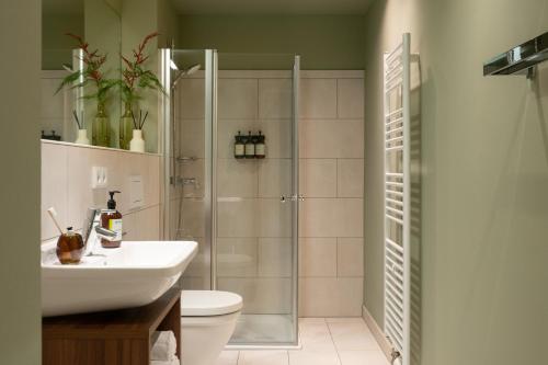 a bathroom with a shower and a sink and a toilet at Bob W Munich City West in Munich