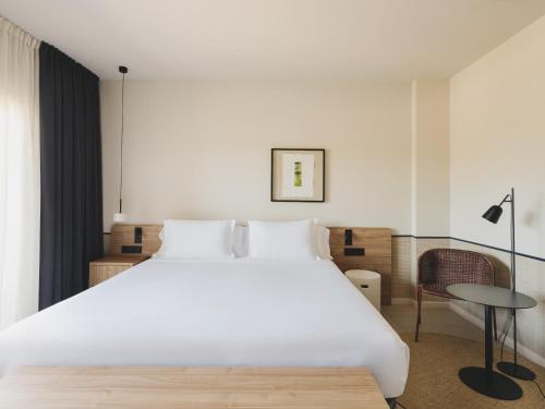 a bedroom with a large white bed and a chair at Hotel Spa Mediterráneo Park in Roses
