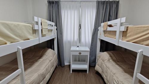 two bunk beds in a room with a couch at Viento Sur Anfitrionas "Centro" in Puerto Madryn