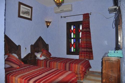 a bedroom with two beds and a stained glass window at Dar Lbakal in Chefchaouene