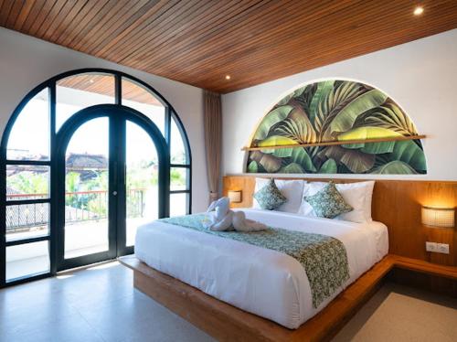 a bedroom with a large bed with two large windows at Tepi Segara Seminyak in Seminyak