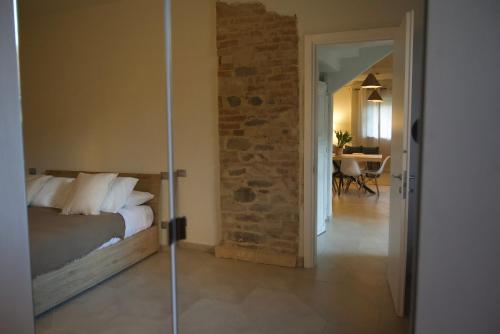 a bedroom with a bed and a brick wall at Langhem Suites Luxury Apartments in Castiglione Falletto