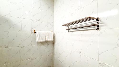 a white tiled bathroom with a towel rack at Agung Guest house Canggu in Dalung
