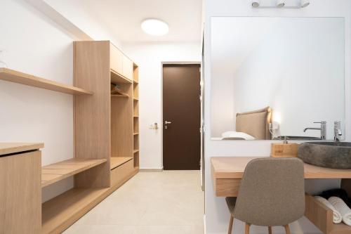 a bathroom with a sink and a desk with a chair at Boomerang Sea View Accommodation in Planos