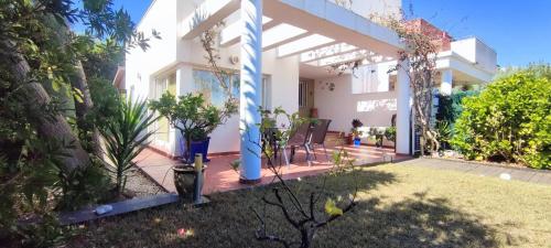 a white house with a porch with trees and plants at Tabarca - Chalet con jardín y piscina comunitaria in Peniscola