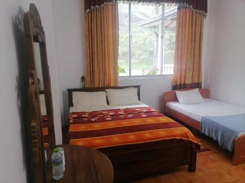 a bedroom with two beds and a window at White Elephant Hotel in Maskeliya