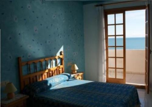 Dormitorio azul con cama y ventana en Apartamentos Rayos de Sol, en Peñíscola