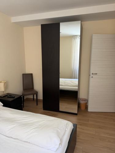 a bedroom with a mirror with a bed and a chair at Appartamenti Camere Schaefer in Tarvisio
