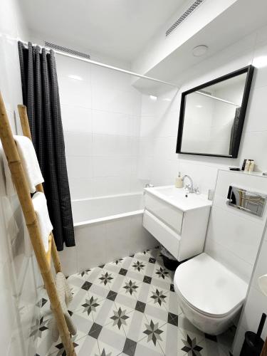 a white bathroom with a toilet and a sink at Apartament Flauta in Mikołajki