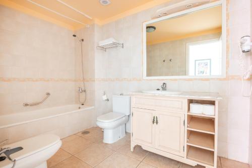a bathroom with a toilet and a sink and a mirror at OBSIDIAN Granada Park in Arona