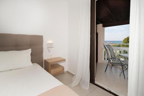 a bedroom with a bed and a balcony with a table at Boomerang Sea View Accommodation in Planos