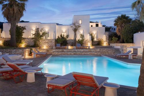 a pool with chairs and a villa in the background at Soleil Hotel Paros in Drios
