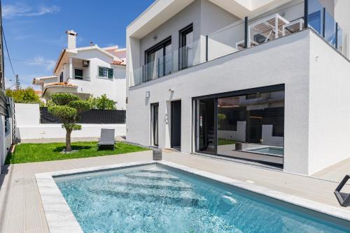 a villa with a swimming pool in front of a house at Poolside oasis by Caparica beach in Charneca