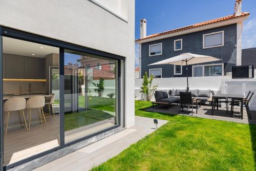 a house with a patio with a table and chairs at Poolside oasis by Caparica beach in Charneca